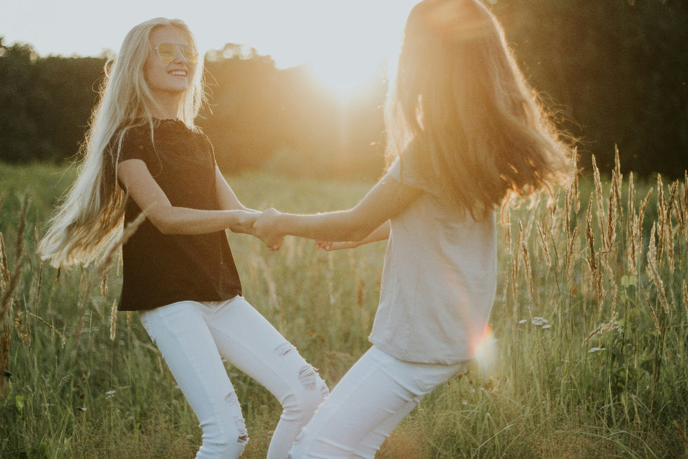 Two people holding hands in a field with a warm, golden light.